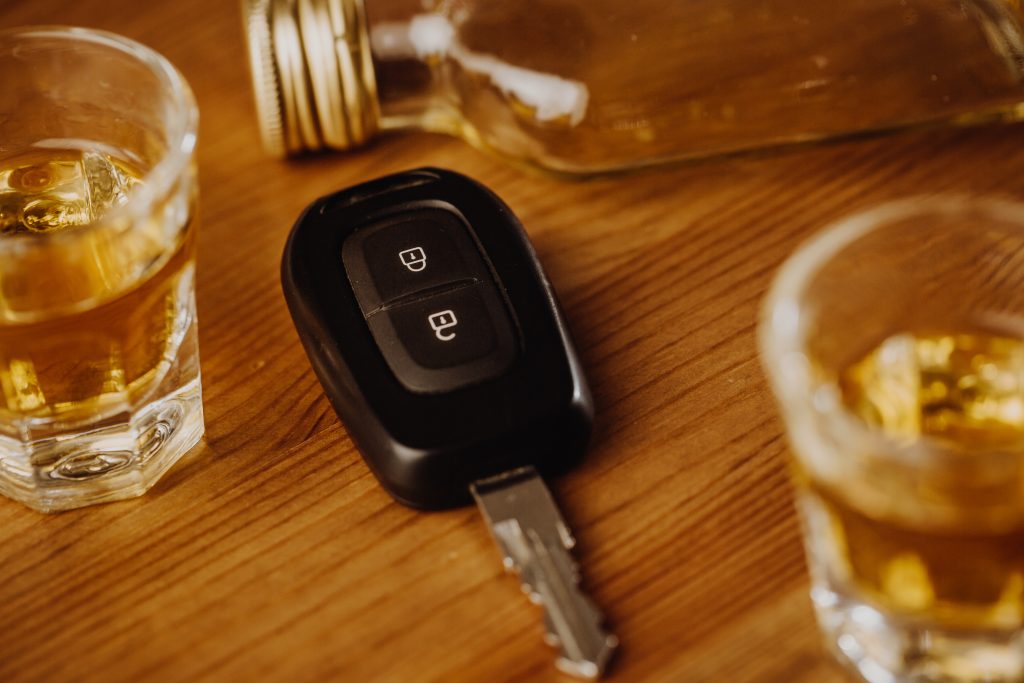 Llave de coche con bebidas alcohólicas sobre una mesa, destacando los peligros de conducir ebrio y su papel en los accidentes de coche en Miami, Florida.